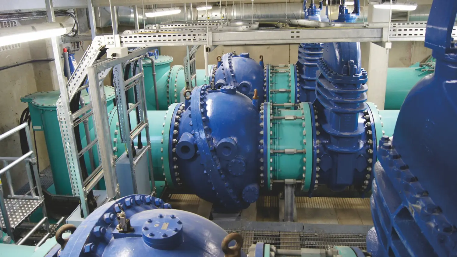 large industrial pumps and blue valves in mechanical room